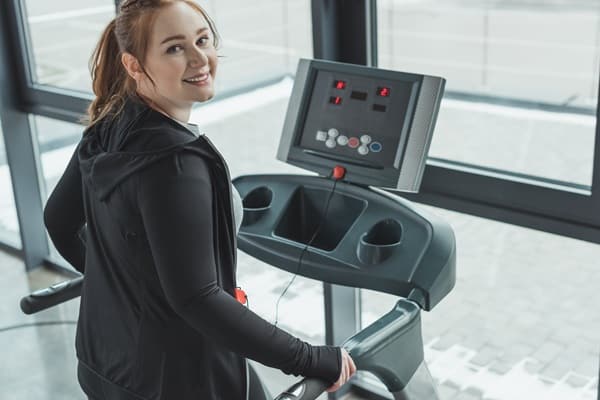 girl smiling while on treadmill in gym